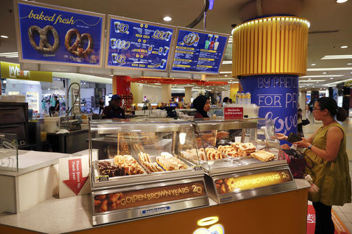 In this Tuesday, Oct. 18, 2016 photo, customer purchase Pretzel at Auntie Anne's at a shopping mall in Kuala Lumpur, Malaysia. Hot dogs, or at least the name, will soon be off the menu for a U.S. fast food chain selling the popular snack in Malaysia. The chain, Auntie Anne's, has been told by Islamic authorities that its popular Pretzel Dog, which contains no dog meat, has to be renamed as it is confusing for Muslim consumers. (AP Photo/Vincent Thian)