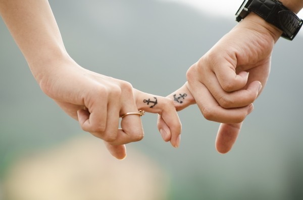 young-couple-holding-hands-with-tatoos-on-fingers