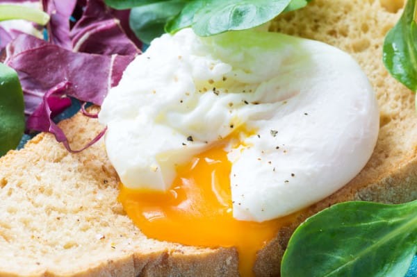 Toast with poached egg and green salad, close up