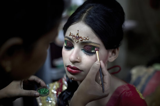 MANIKGANJ, BANGLADESH - AUGUST 20: 15 year old Nasoin Akhter has her makeup done at a beauty parlour on the day of her wedding to a 32 year old man, August 20, 2015 in Manikganj, Bangladesh. In June of this year, Human Rights Watch released a damning report about child marriage in Bangladesh. The country has one of the highest rates of child marriage in the world, with 29% of girls marrying before the age of 15, and 65% of girls marrying before they turn 18. The detrimental effects of early marriage on a girl cannot be overstated. Most young brides drop out of school. Pregnant girls from 15-20 are twice as likely to die in childbirth than those 20 or older, while girls under 15 are at five times the risk. Research cites spousal age difference as a significant risk factor for violence and sexual abuse. Child marriage is attributed to both cultural tradition and poverty. Parents believe that it "protects" girls from sexual assault and harassment. Larger dowries are not required for young girls, and economically, women's earnings are insignificant as compared to men's. (Photo by Allison Joyce/Getty Images)