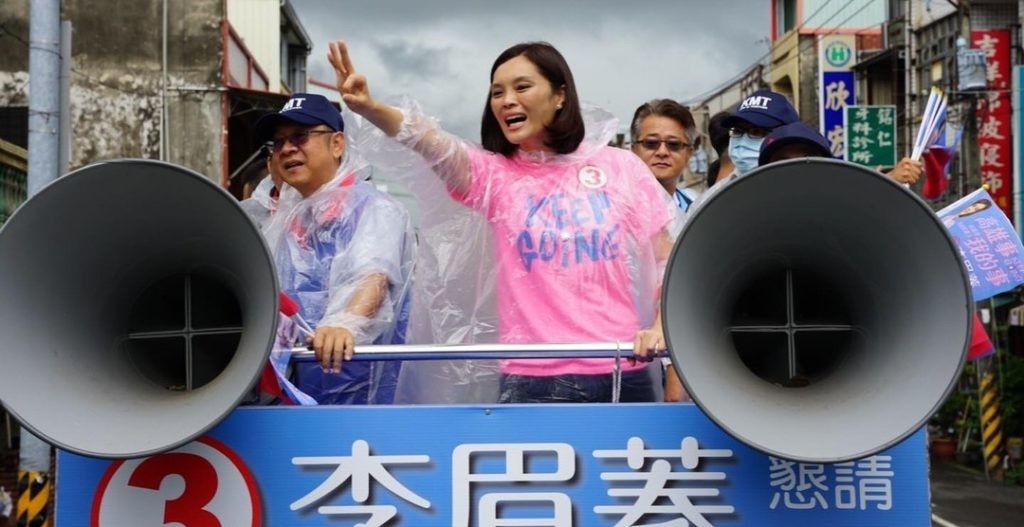 李眉蓁身穿透明雨衣，站在競選車上，臉上漾著笑容向車下的群眾揮手