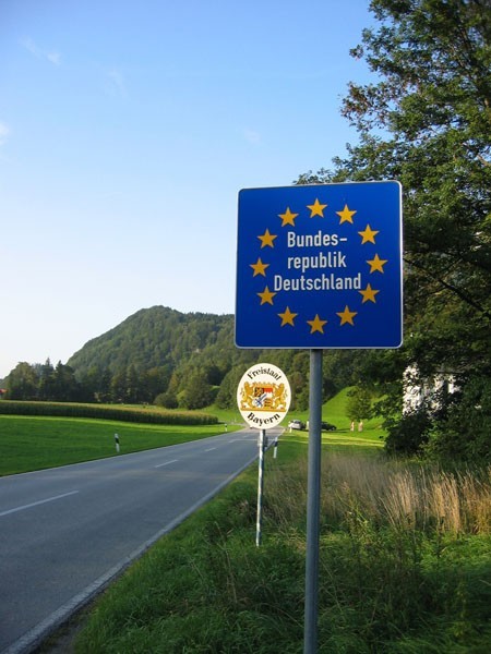  圖為德國與奧地利之間的邊境，沒有一般國界上設有邊境檢查站及圍欄等阻隔設施，而僅立有歡迎指示牌。較大的藍色指示牌說明已進入德意志聯邦共和國，較小的白色指示牌表明進入德國巴伐利亞州（圖片來源：原文）